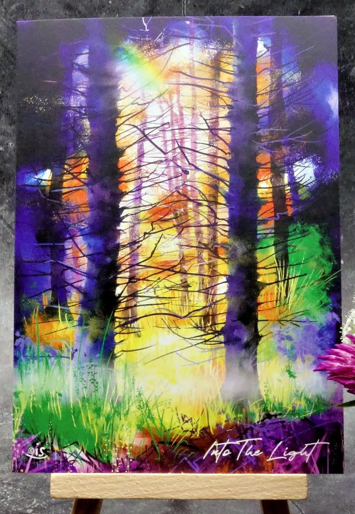 Larger image titled Into The Light, showing an A6 size greetings card, blank inside, on a small easel depicting a colourfully lit woodland scene.