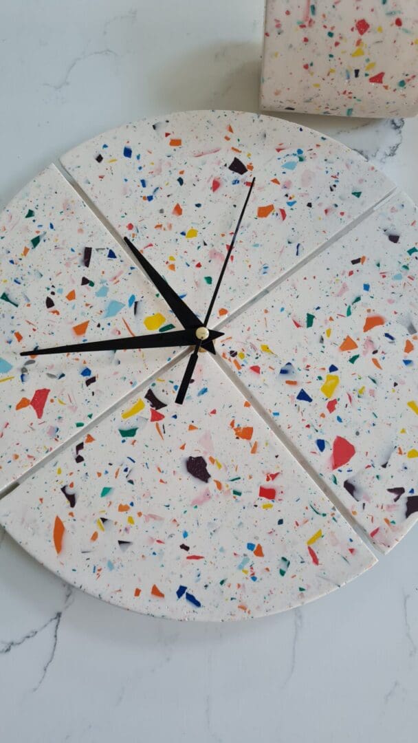 Round terrazzo clock with a white base and multi-coloured contrasting chips