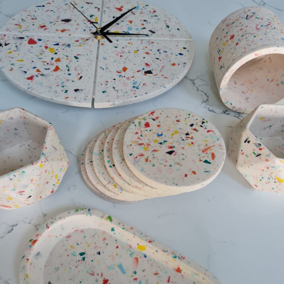 Round terrazzo clock with a white base and multi-coloured contrasting chips