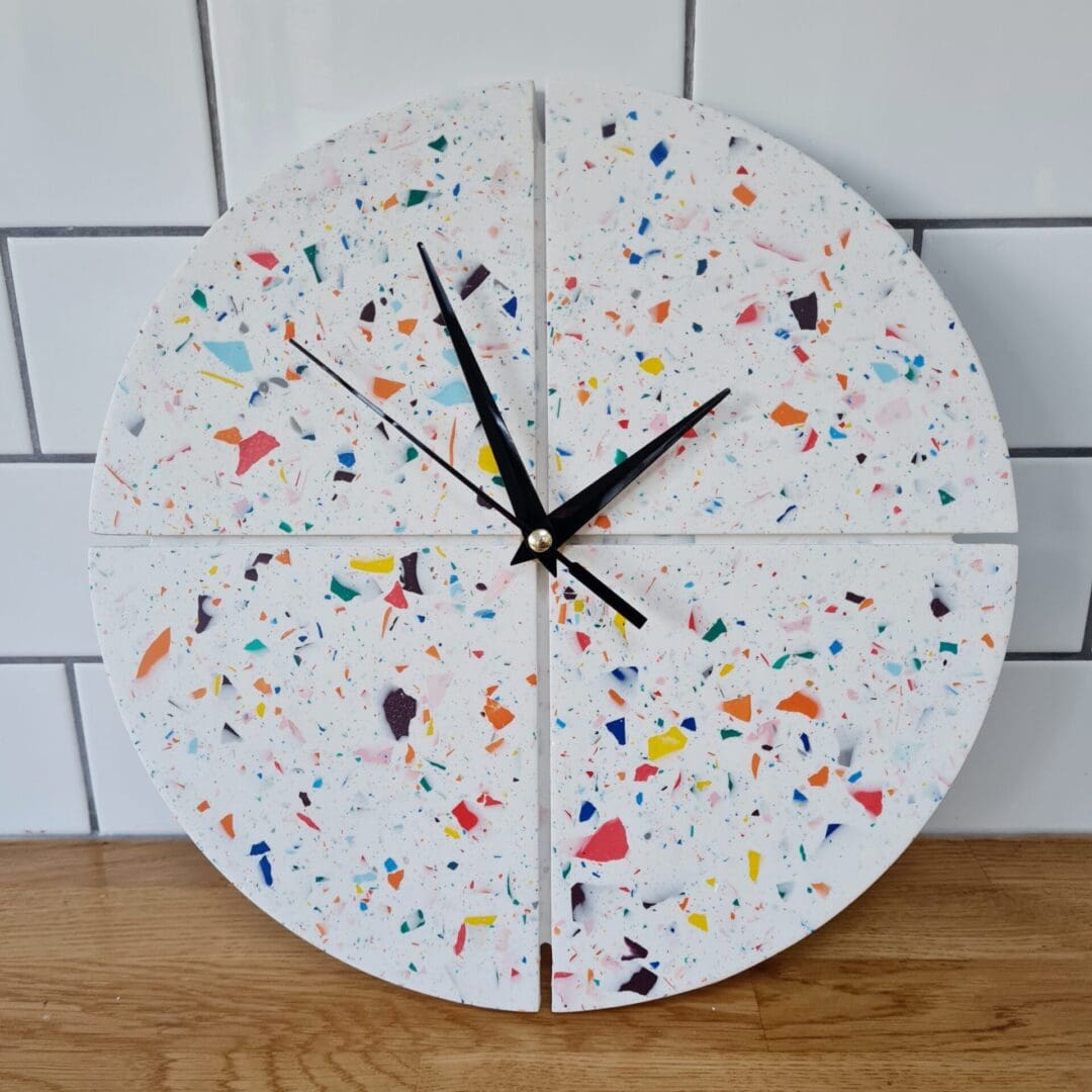 Round terrazzo clock with a white base and multi-coloured contrasting chips