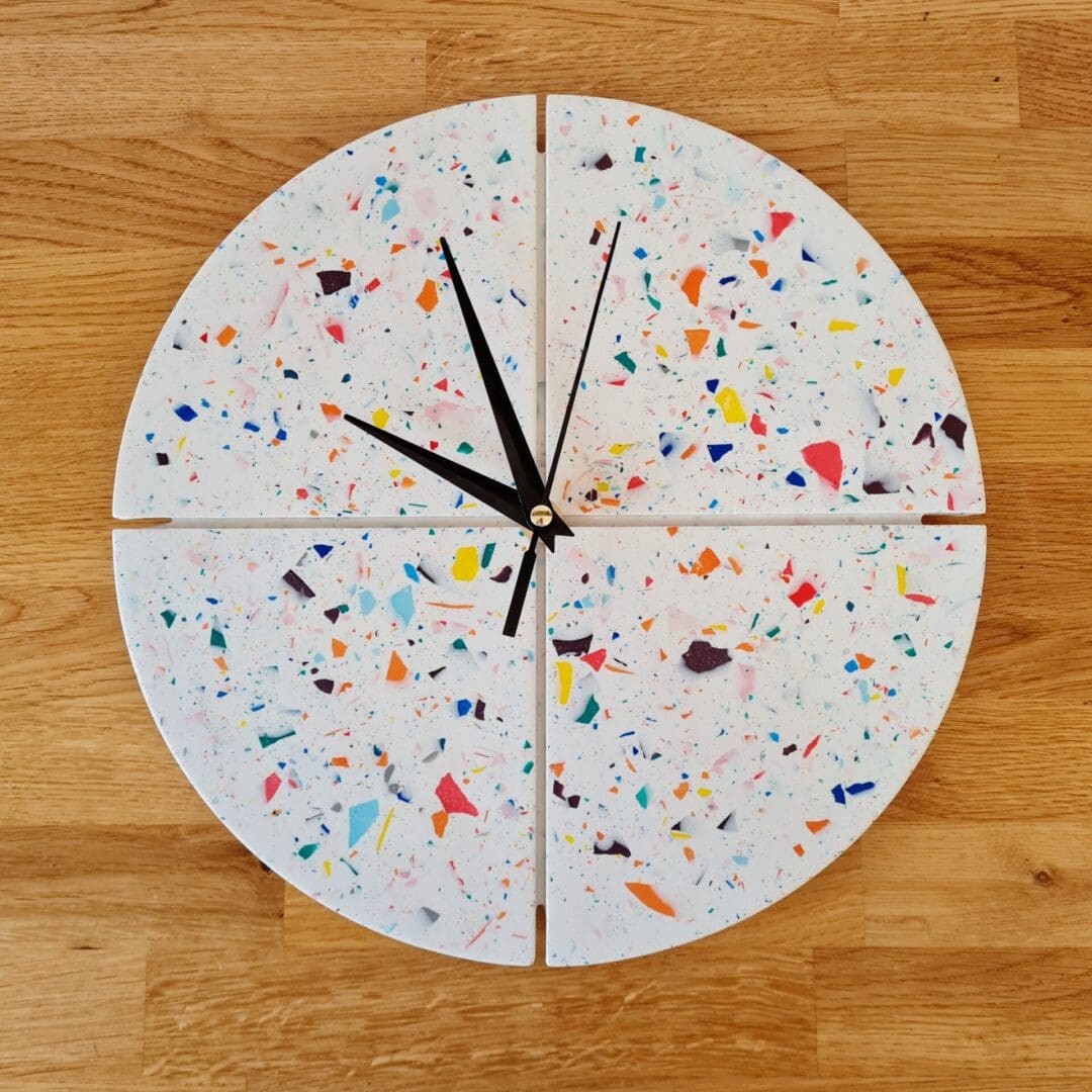 Round terrazzo clock with a white base and multi-coloured contrasting chips