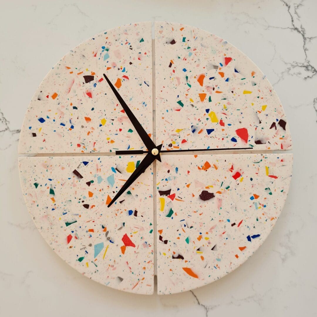 Round terrazzo clock with a white base and multi-coloured contrasting chips