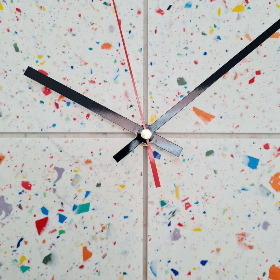 Round terrazzo clock with a white base and multi-coloured contrasting chips