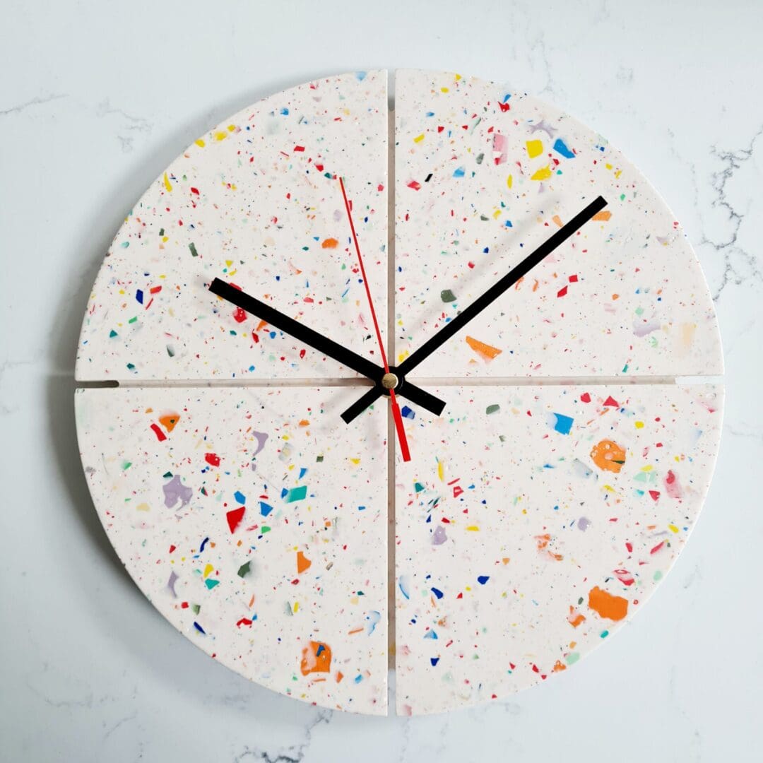 Round terrazzo clock with a white base and multi-coloured contrasting chips