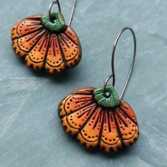 A pair of quirky, handmade orange pumpkin inspired earrings in folk art style for autumn and Halloween.