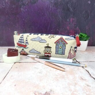 Large, boxy, beach scene pencil case with a faux suede tassel zip pull.