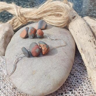 a pair of earrings featuring grey/orange beach pebbles stacked to create a dangly earring