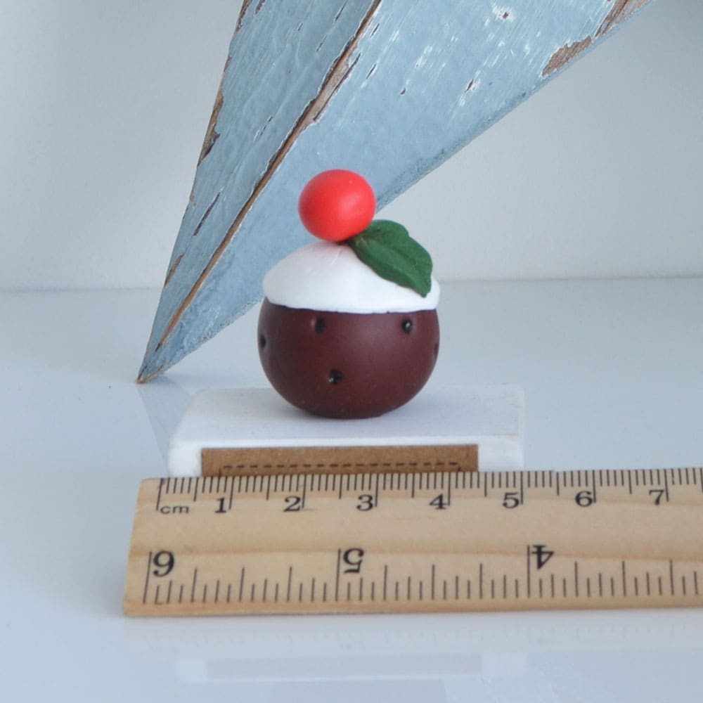 Clay Christmas Pudding ornament set on a white wooden base with the pun 'A Jolly Pud Christmas.