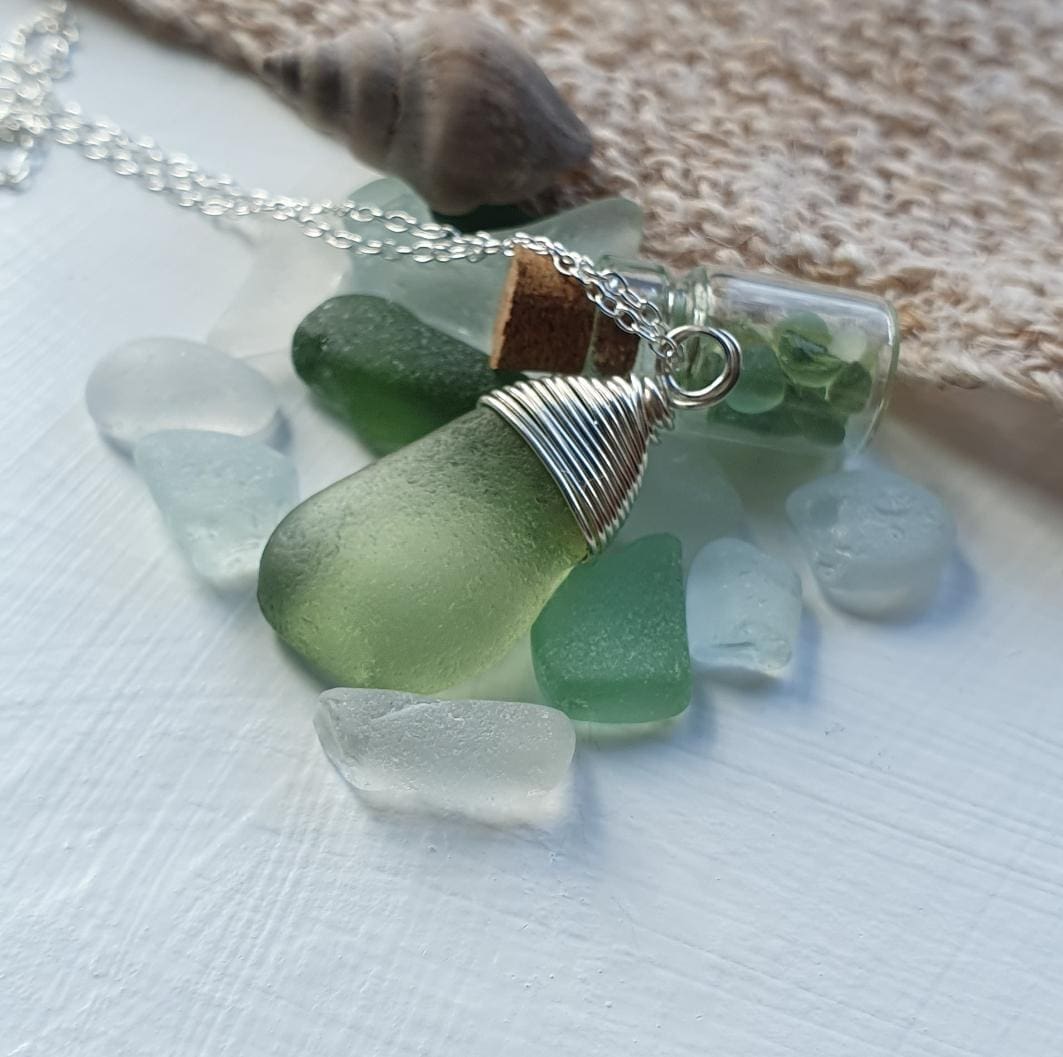 pale green seaglass wrapped with silver wire nestling amongst a pile of sea glass