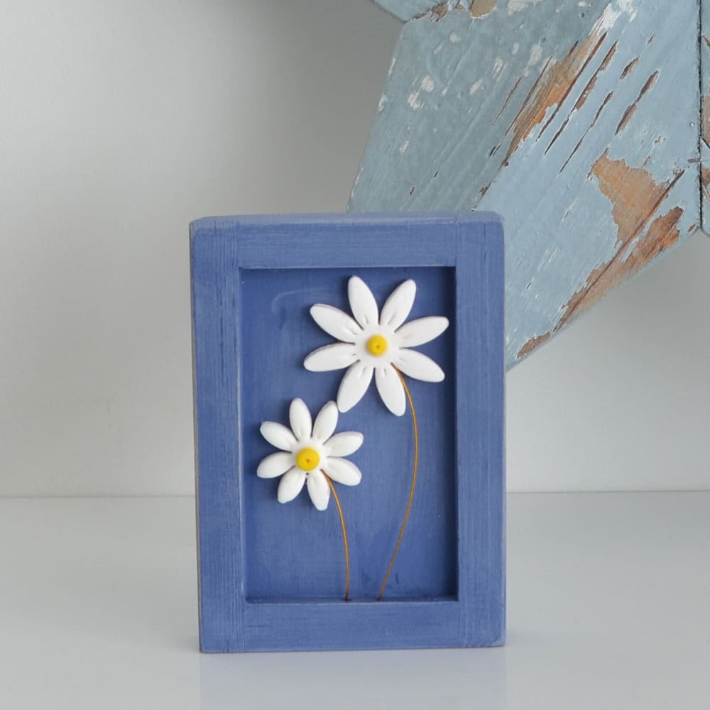 Miniature handmade wooden open frame in a distressed blue chalk paint with two small clay daisy flowers