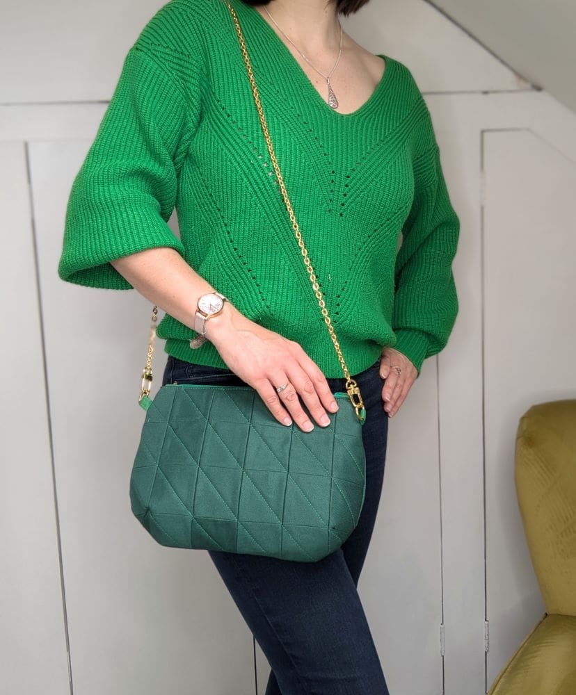 A green quilted shoulder bag shown on a woman's body to show the size and proportions