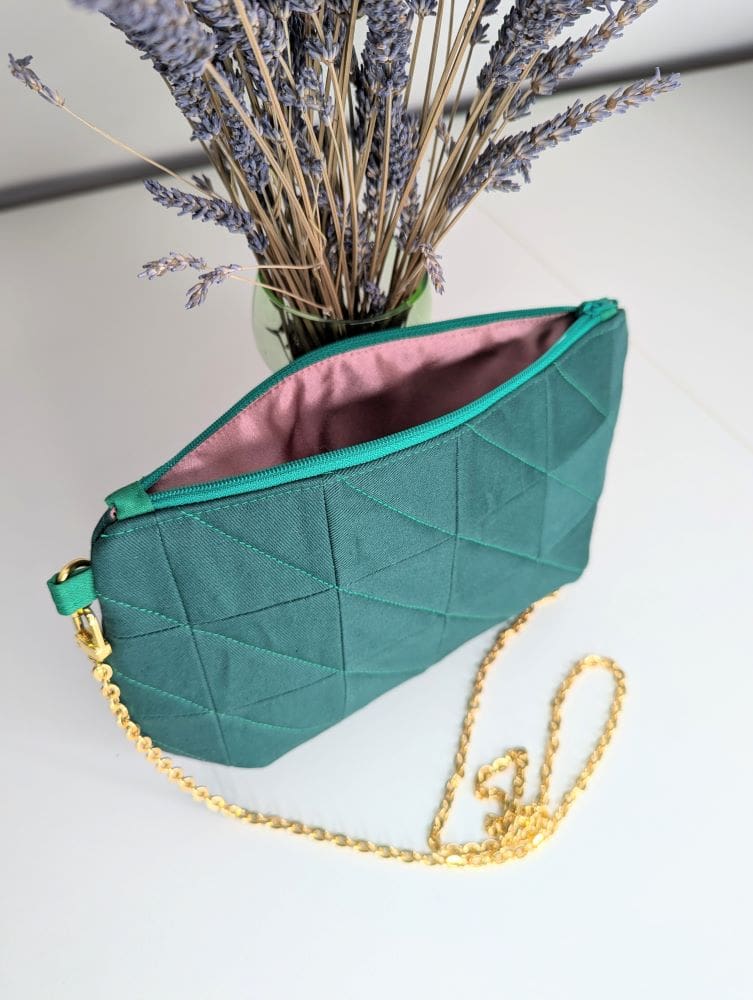 Forest green evening bag showing the pink lining and gold coloured chain