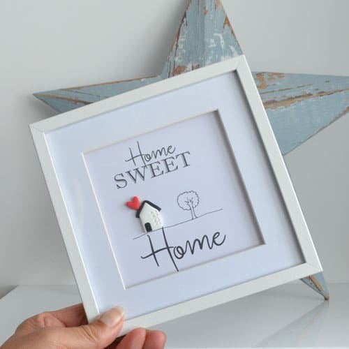 White frame with a Home Sweet Home sign inside and a little clay house with heart and a hand drawn tree.