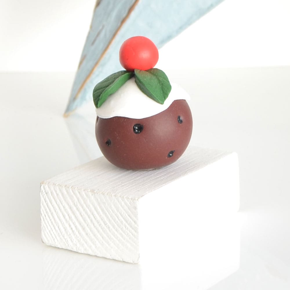 Clay Christmas Pudding ornament set on a white wooden base with the pun 'A Jolly Pud Christmas.