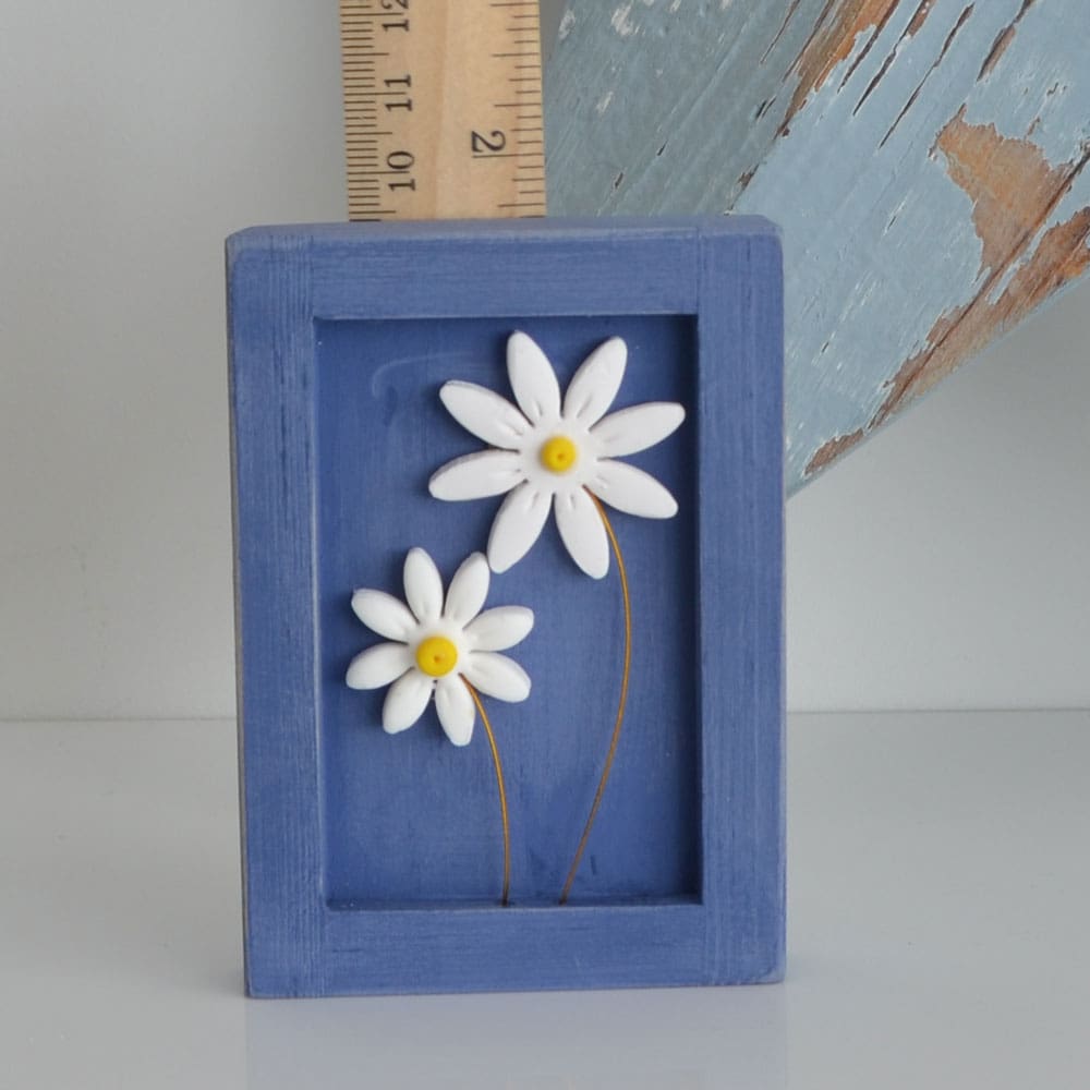 Miniature handmade wooden open frame in a distressed blue chalk paint with two small clay daisy flowers