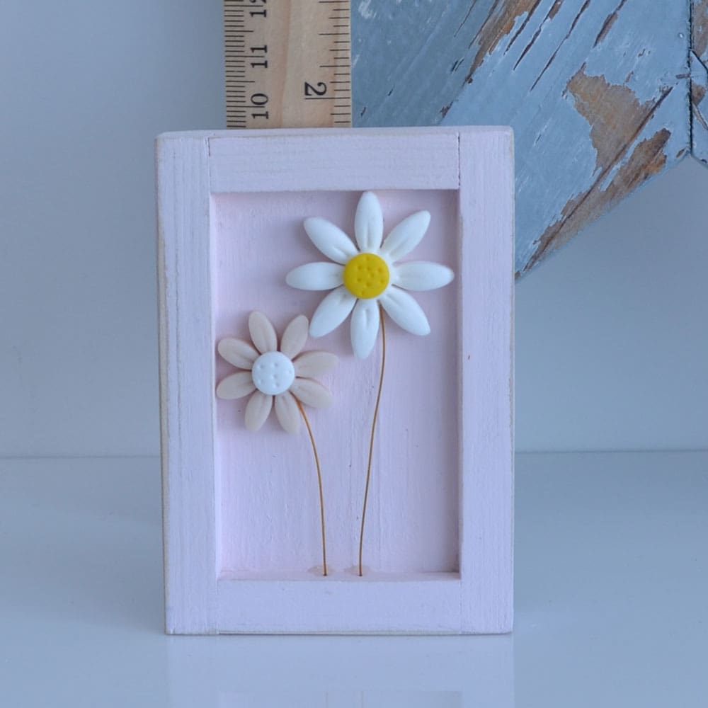 Miniature handmade wooden open frame in a distressed pink with two small clay daisy flowers in white and pink