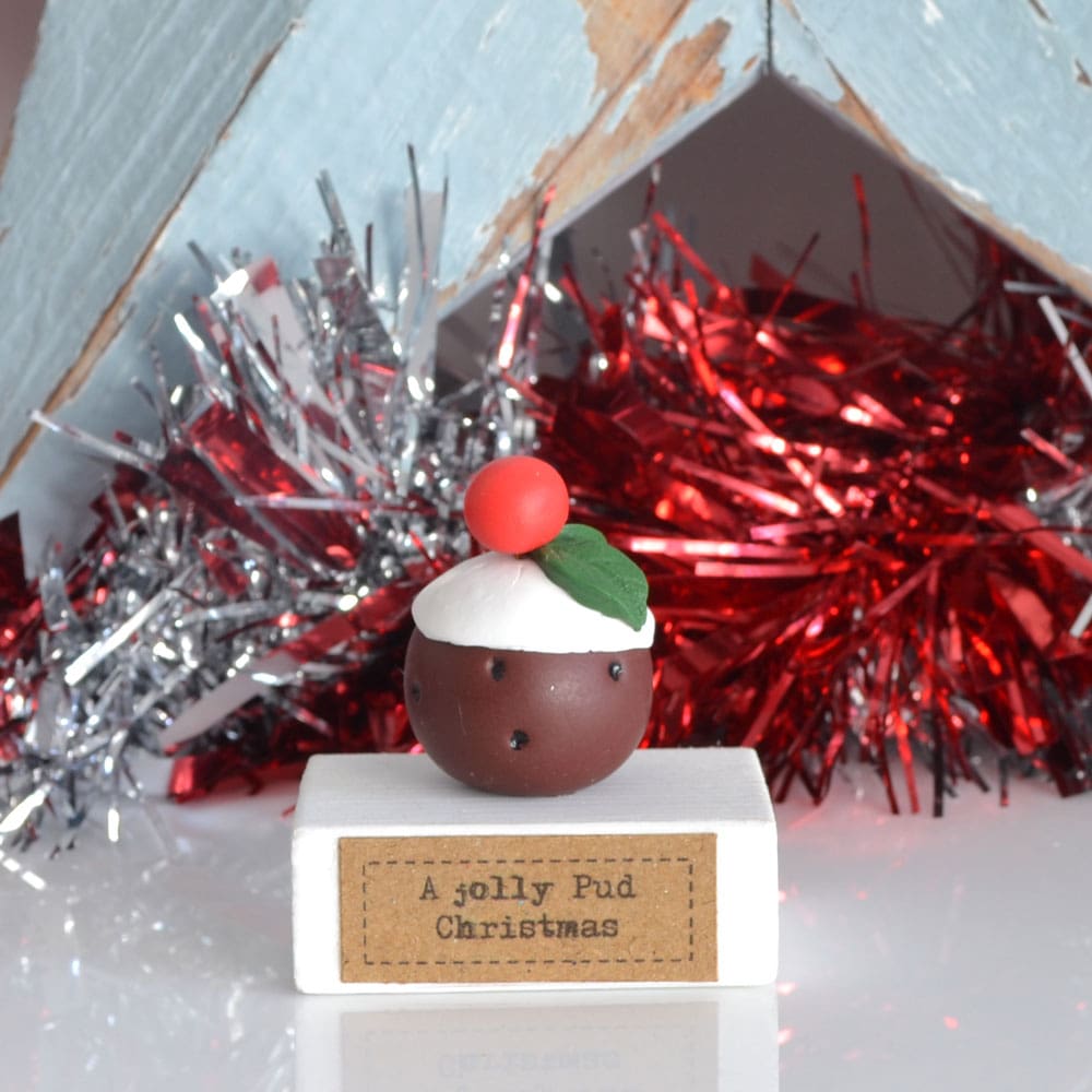 Clay Christmas Pudding ornament set on a white wooden base with the pun 'A Jolly Pud Christmas.