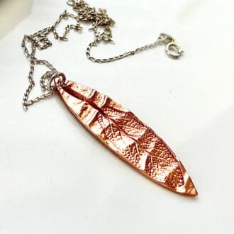 A leaf imprinted pure copper pendant with a sterling silver chain in a white gift box.