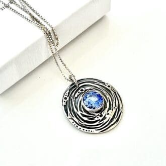 A fine silver pendant with 6mm. blue zirconia stone displayed on a white background.