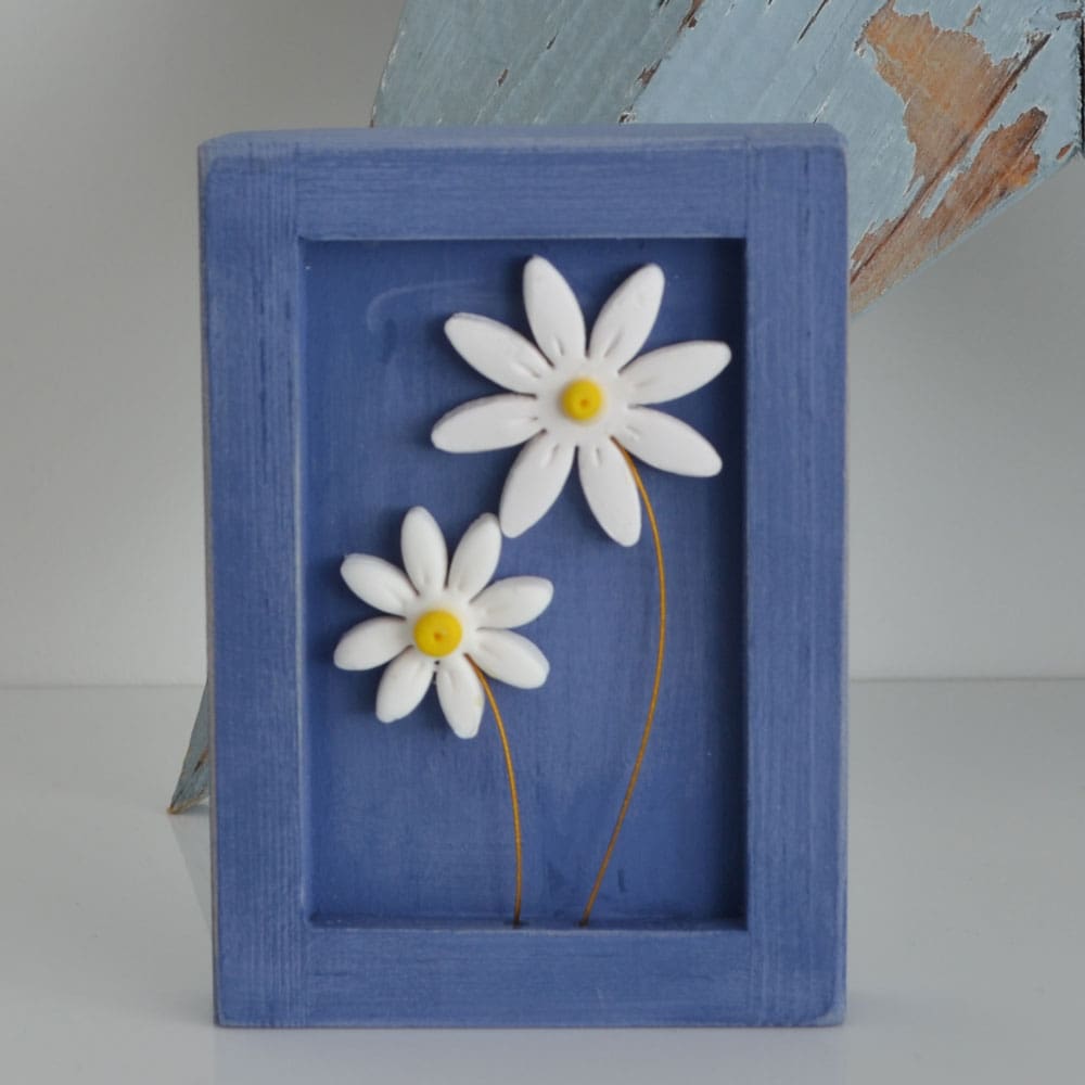 Miniature handmade wooden open frame in a distressed blue chalk paint with two small clay daisy flowers