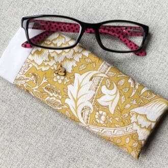 Mustard and white floral fabric glasses case with wooden bee decoration