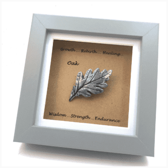 Cold-cast metal Oak leaf sculpture in a square box frame with words associated with the Oak tree printed around it.