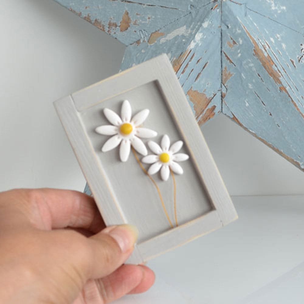 Miniature handmade wooden open frame in a distressed grey with two small clay white daisy flowers