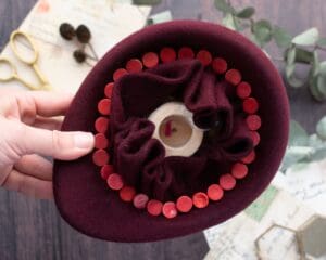 felt hat pinned on a millinery block held in hand