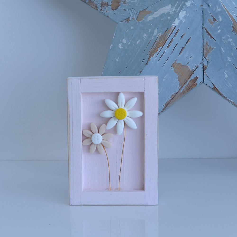 Miniature handmade wooden open frame in a distressed pink with two small clay daisy flowers in white and pink