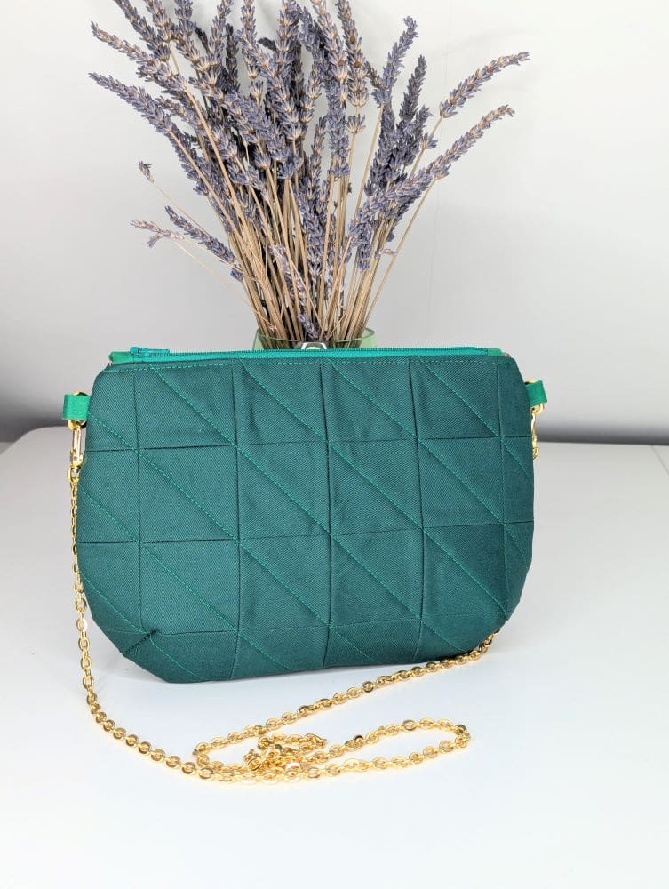 Green, quilted clutch bag with a gold coloured chain