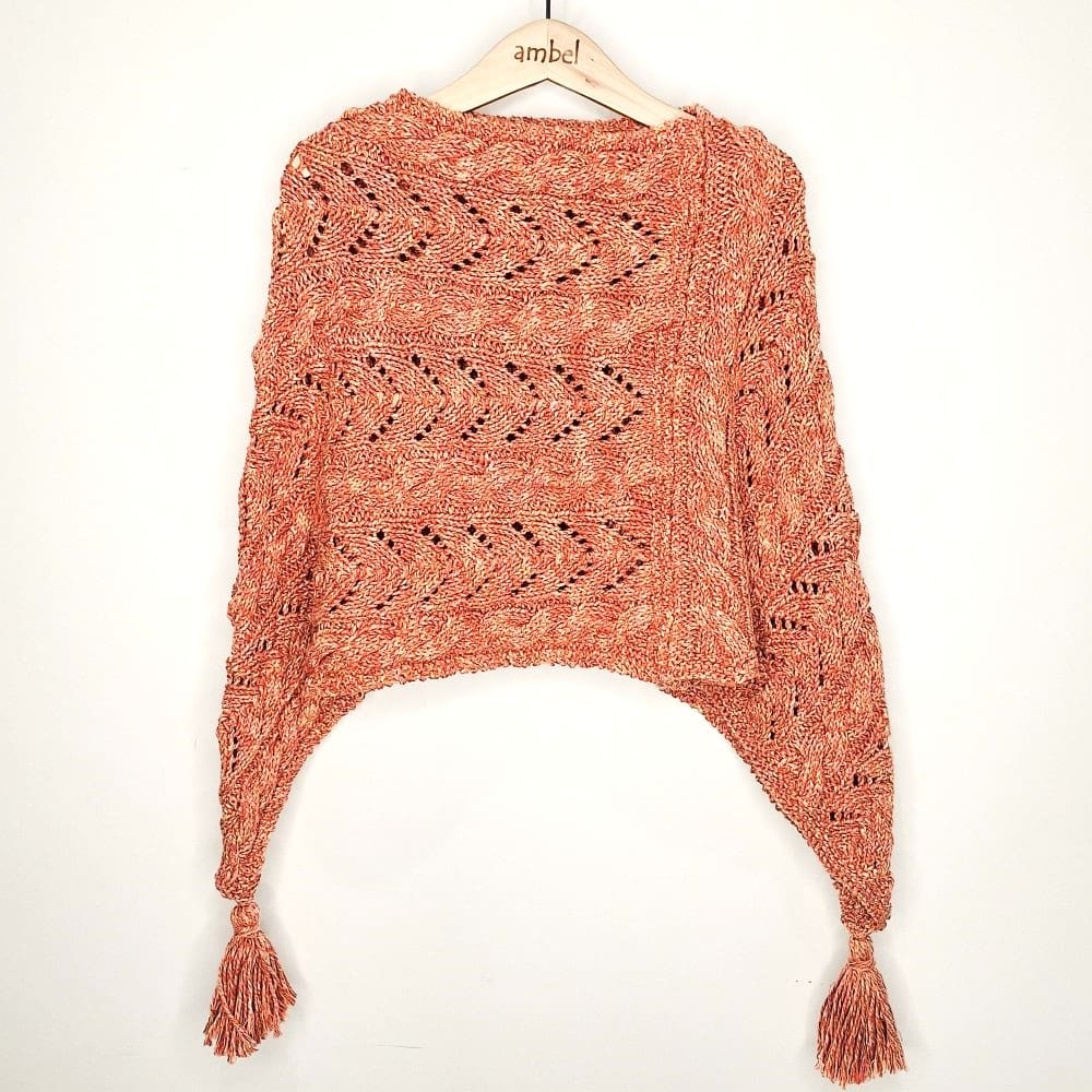 A striking hand-knitted girls poncho is soft coral and orange tones, ideal for autumn days.