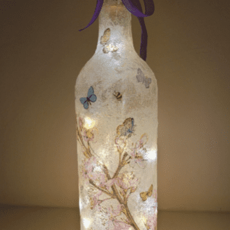 lit up Standard wine bottle with flower and butterfly design. Purple ribbon tied around the neck