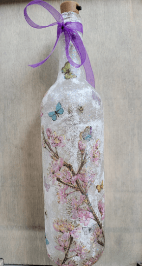 standard wine bottle with flower butterfly design. Purple ribbon tied around the neck