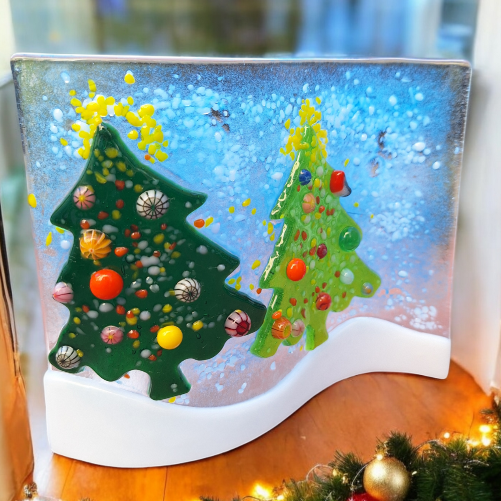 Handmade fused glass Christmas wave featuring two green Christmas trees with colourful ornaments, set against a snowy blue background. Freestanding home decor, perfect for adding festive charm to your living space or gifting as a unique Christmas decoration.