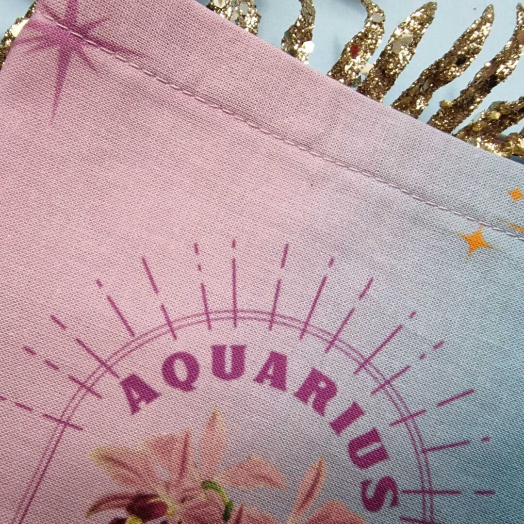 photo of a handmade cotton pouch with digital print of aquarius birth flower, orchid in purples and blues with eco-satin ribbon