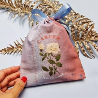 photo of a handmade cotton pouch with digital print of cancer's birth flower, the white rose.