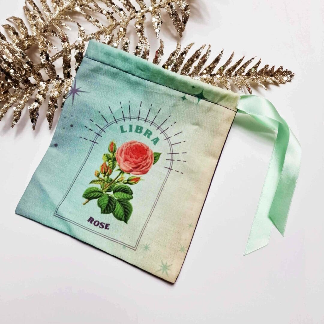 photo of a handmade cotton pouch with digital print of the libra birth flower, rose. finished with an eco-satin ribbon tie