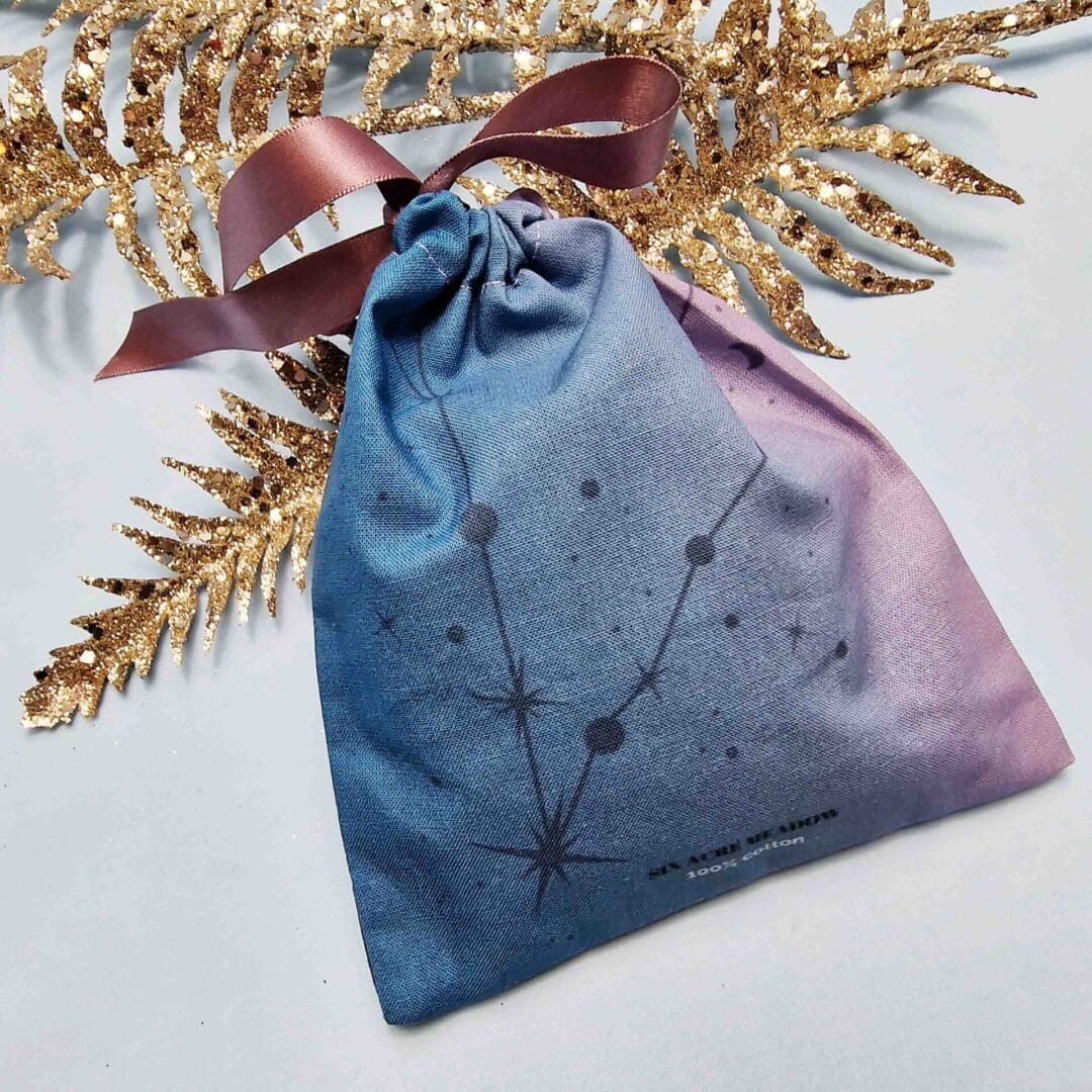 photo of a handmade cotton pouch with a digital print of the pisces birth flower, the water lily finished with an eco-satin mauve ribbon