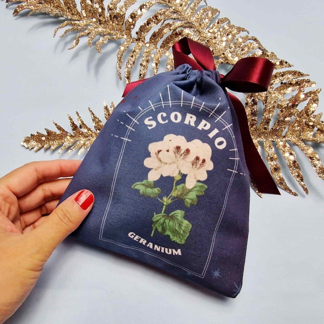 photo of a handmade cotton pouch featuring a digitial print of scorpio's birth flower, the geranium