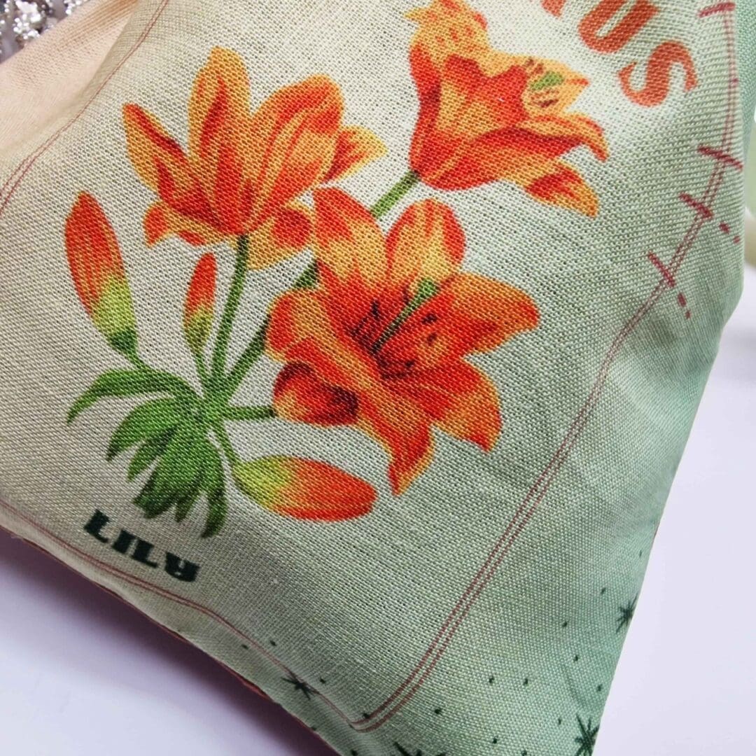 photo of a handmade cotton pouch featuring a digital print of the taurus birth flower, the orange lily, finished with eco-satin ribbon