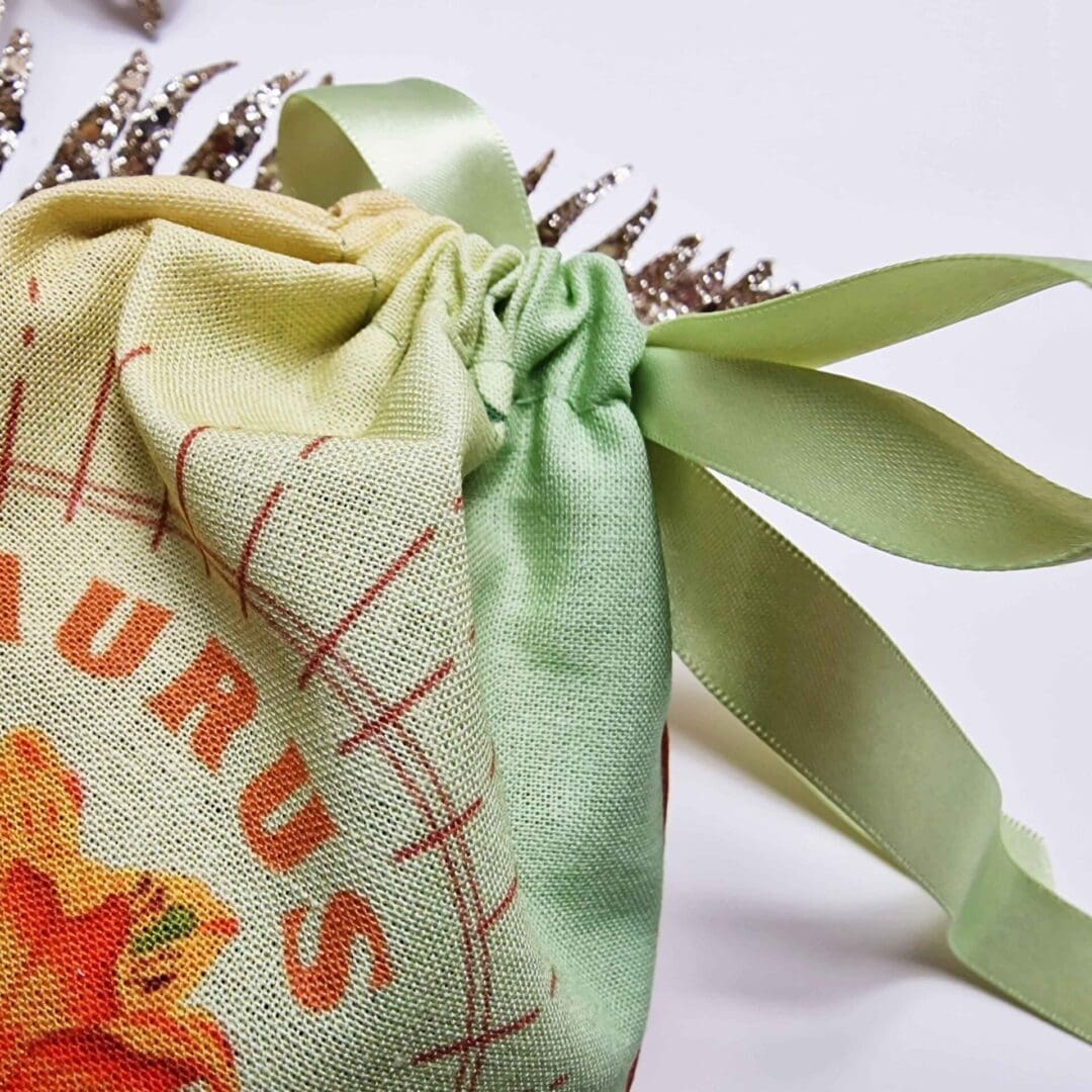 photo of a handmade cotton pouch featuring a digital print of the taurus birth flower, the orange lily, finished with eco-satin ribbon