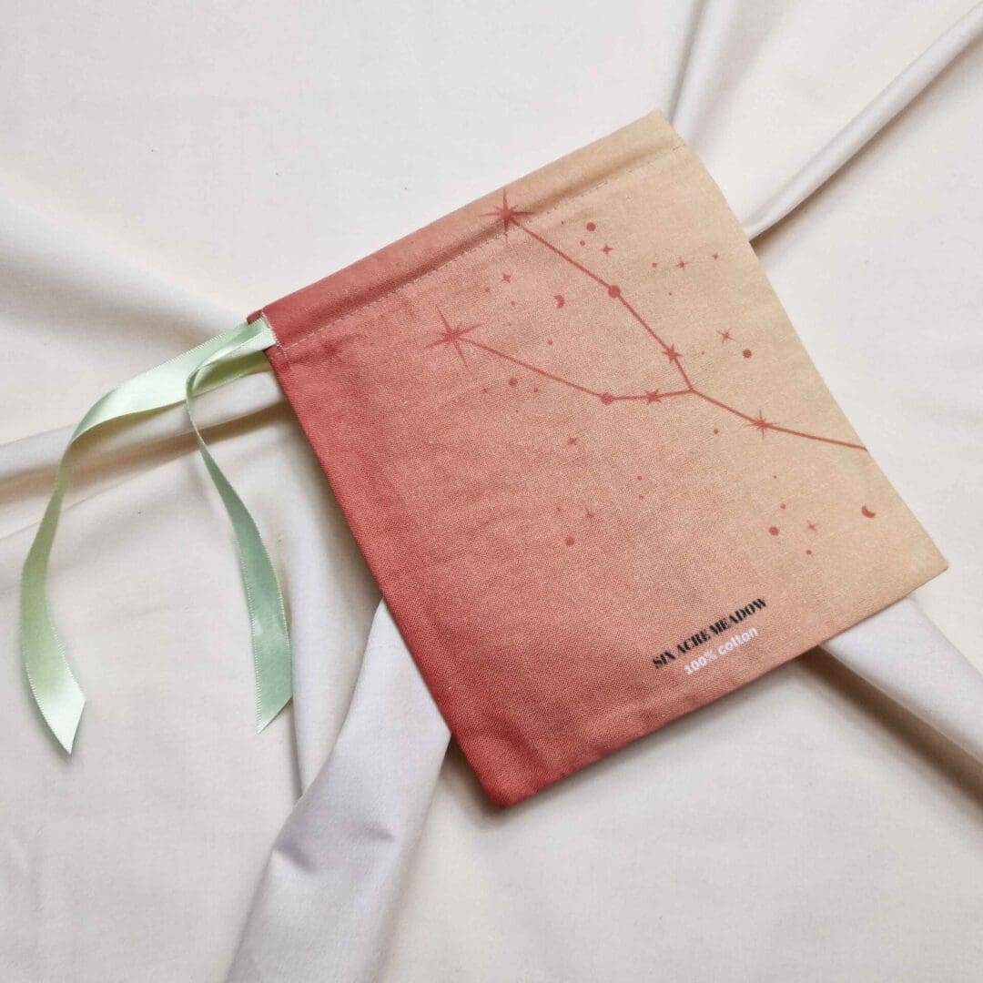 photo of a handmade cotton pouch featuring a digital print of the taurus birth flower, the orange lily, finished with eco-satin ribbon