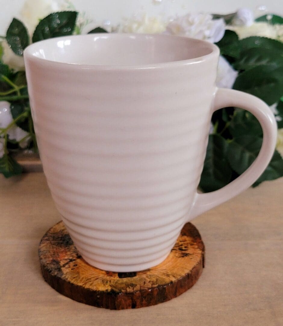 white mug sitting on a wood slice coaster