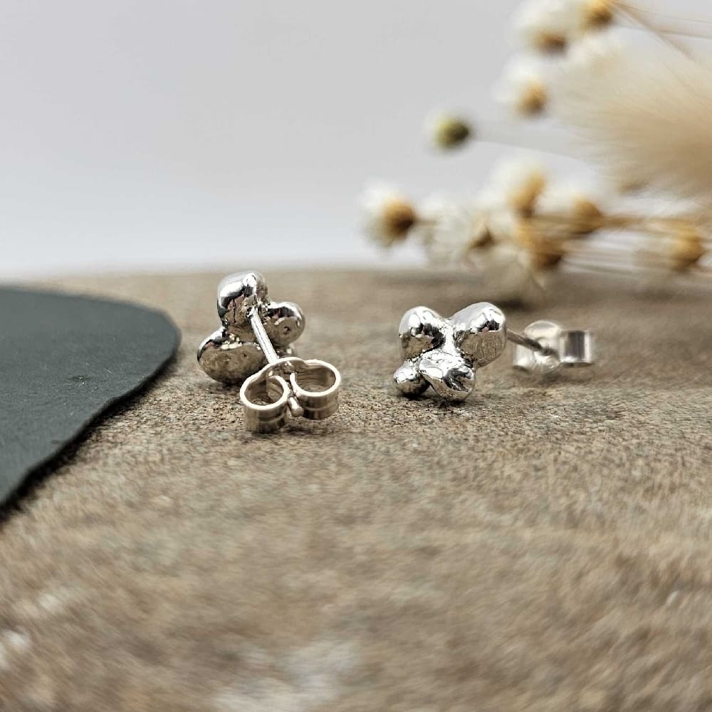 Pair of handcrafted recycled sterling silver cluster bead stud earrings displayed hanging on decorative stone