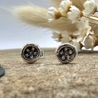 Handcrafted recycled oxidised sterling silver forget me not floral round stud earrings displayed on decorative stone