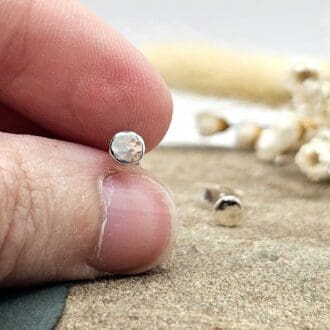 Handcrafted recycled oxidised sterling silver hammered 4.5mm round stud earrings held between jeweller's fingers