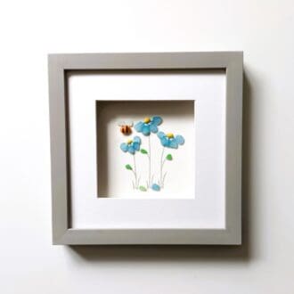 three forget me not flowers made from Cornish sea glass set inside a 24cm square frame