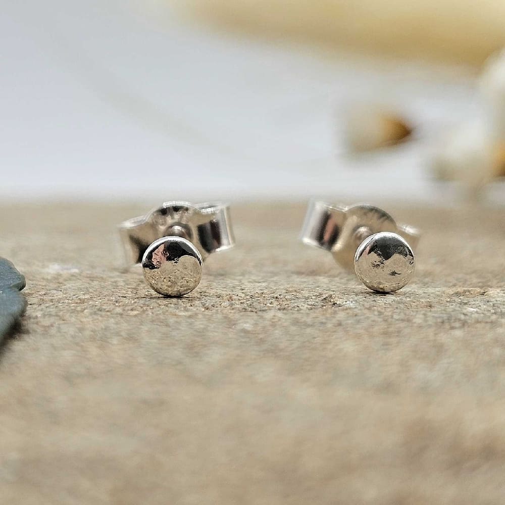 Handcrafted recycled oxidised sterling silver hammered 3mm round stud earrings displayed on decorative sand coloured stone