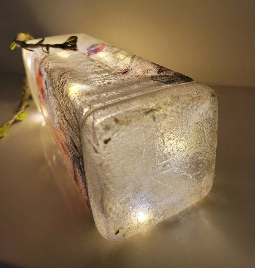 Lit up Square glass gin bottle with fox detailing. Leafy jute twine tied around the neck of the bottle. Bottle showing square underside