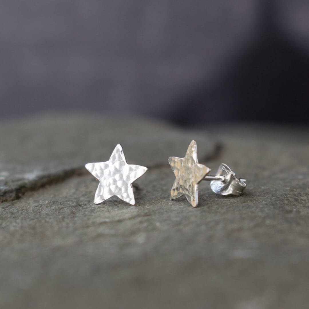 silver star stud earrings with a hammred texture, resting on a slate slab